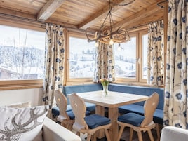 Una habitación acogedora con techo de madera, una mesa redonda con sillas con cojines azules y un banco con cojines azules.