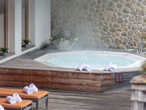 Ein Wellnessbereich mit Whirlpool, Holzliegen und Handtüchern.