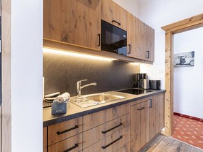 Eine moderne Küche mit Holzschränken, einer Edelstahl-Spüle und einer Mikrowelle.