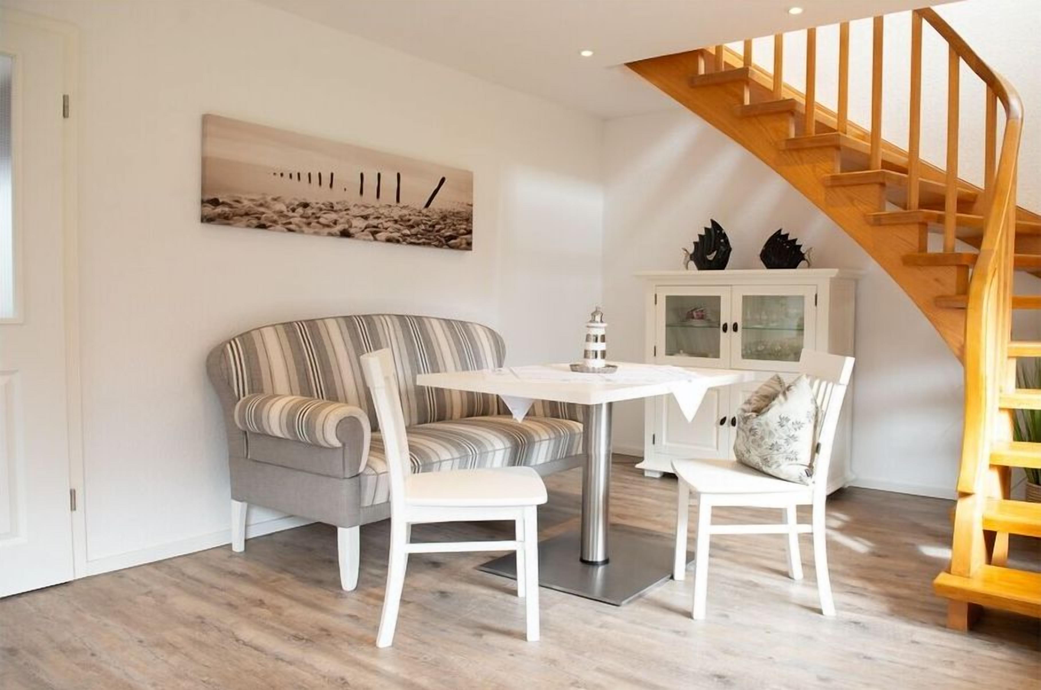 Una sala de estar con un sofá, dos sillones, una mesa, un aparador y una escalera de madera.