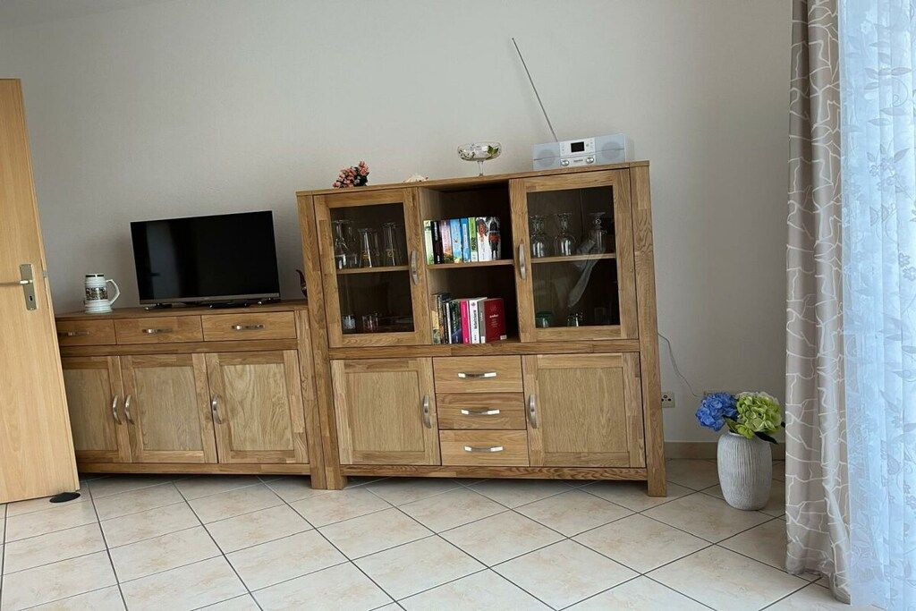 Un mueble de madera con un televisor, libros y adornos.