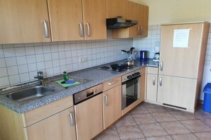 A kitchen with wooden cabinets, a stainless steel sink, a stove, and a refrigerator. - in the Damaris house || Zingst (Zingst)