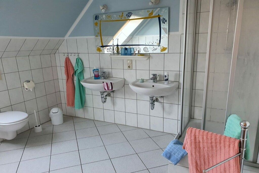 Un baño con dos lavamanos, un inodoro y una ducha.