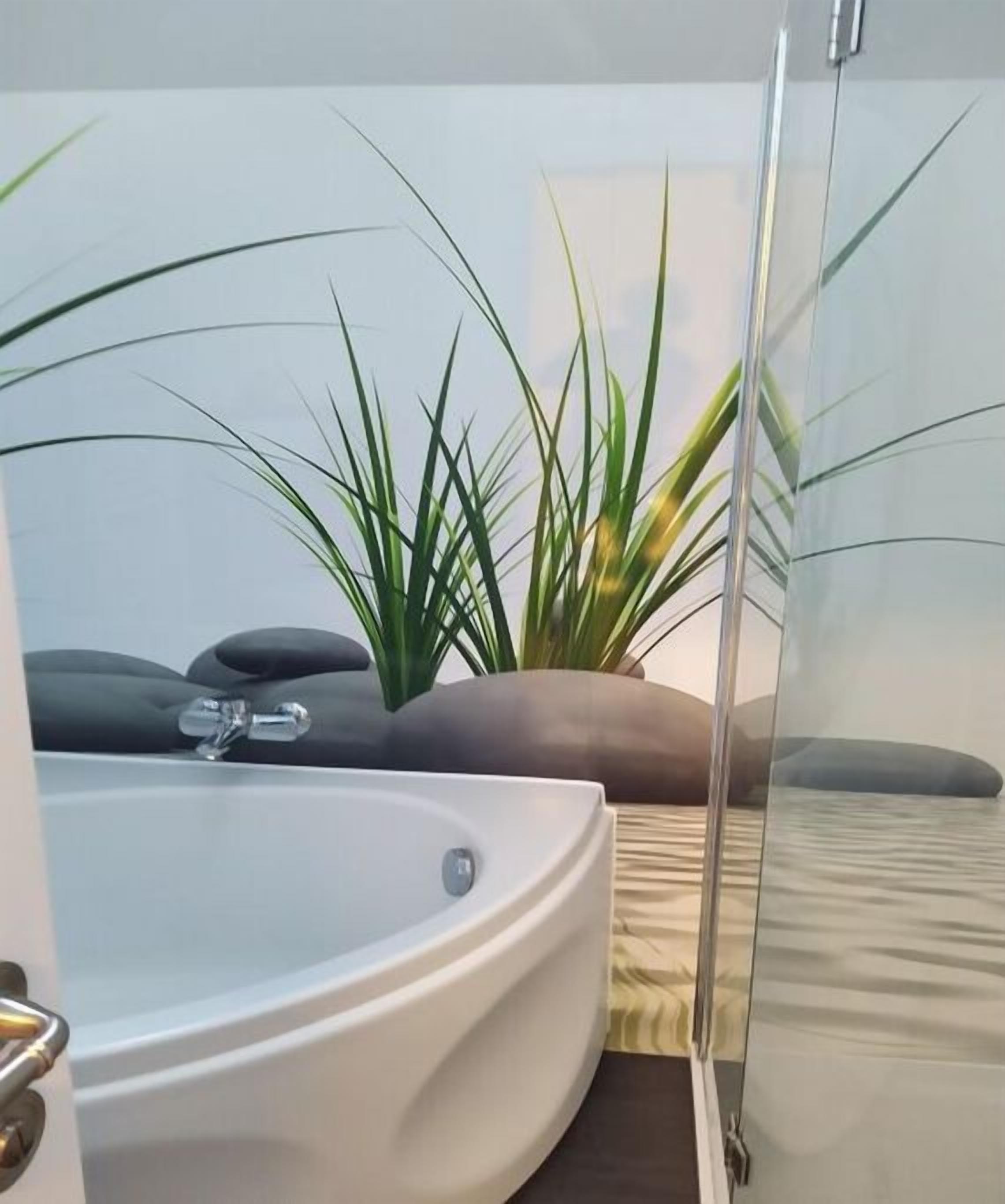 Un baño moderno con bañera, cabina de ducha de vidrio y una planta en maceta.