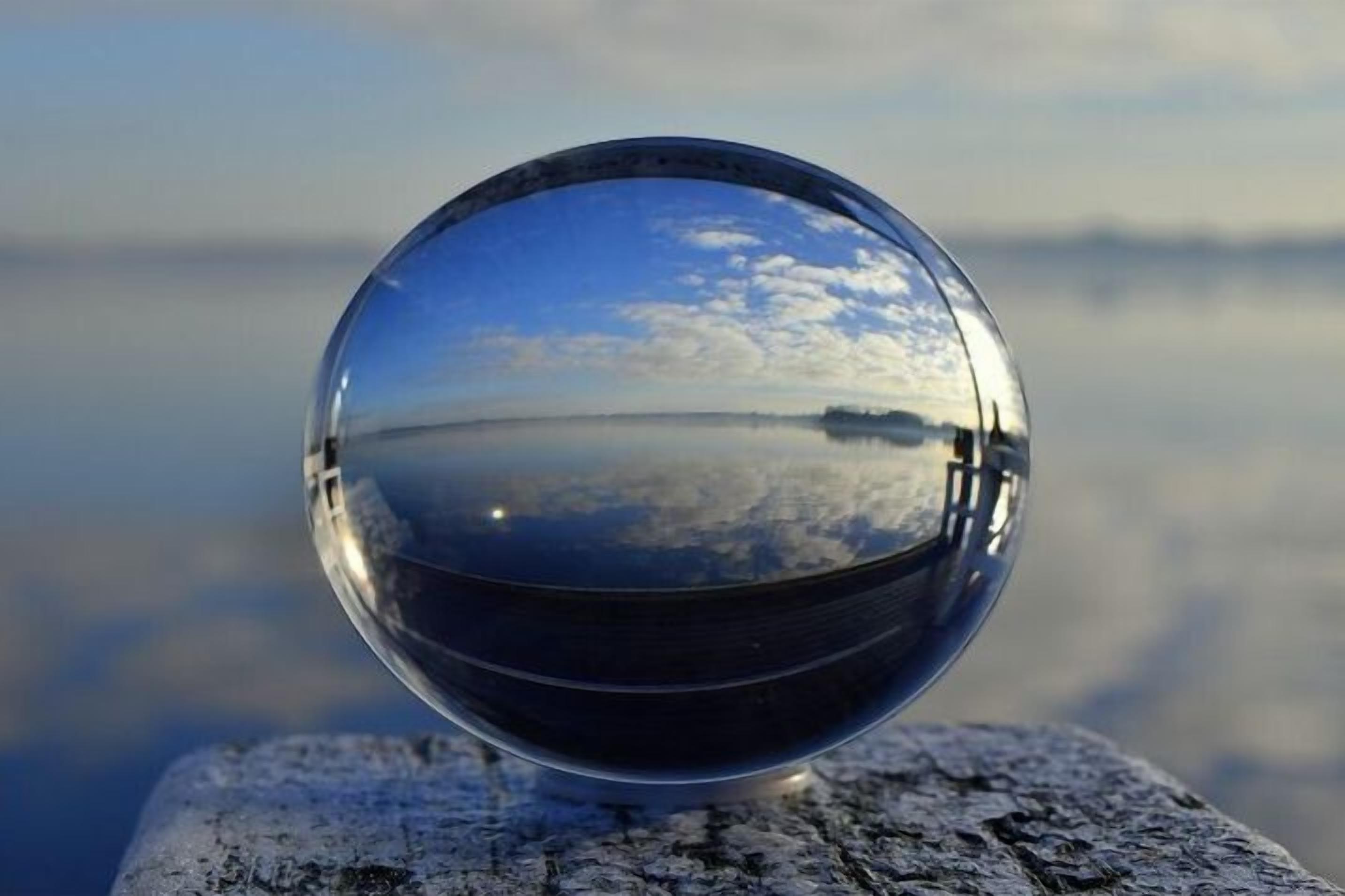 Une sphère de verre transparent qui reflète un paysage.