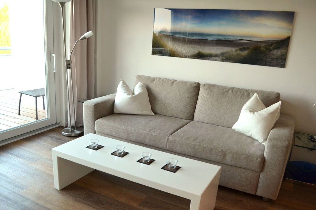 A living room with a sofa, a coffee table, and a painting on the wall.