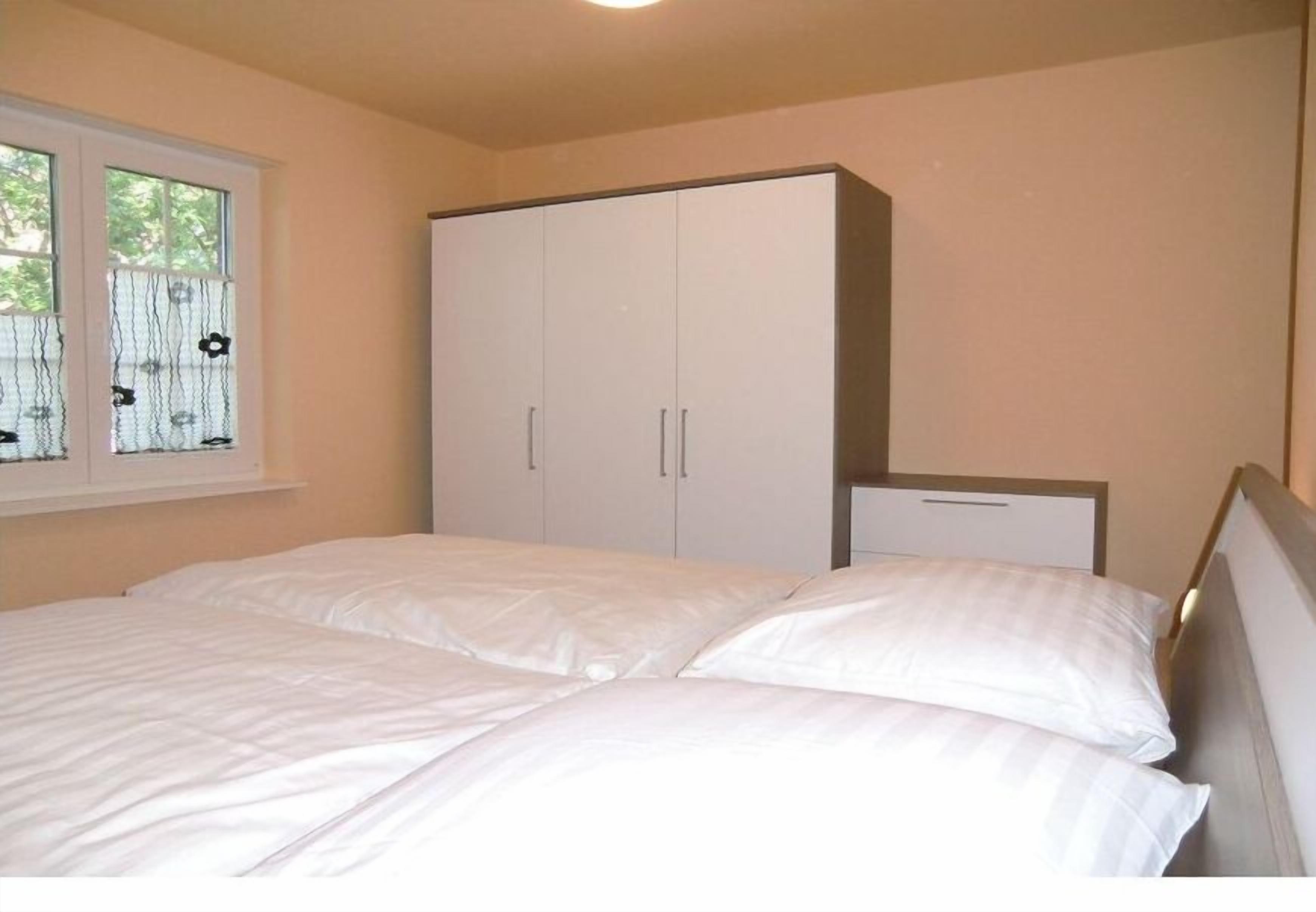 Une chambre à coucher avec un lit, une armoire et une fenêtre donnant sur un beau paysage.