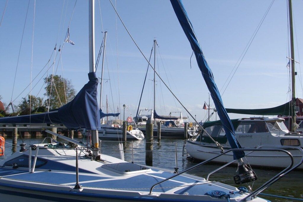 Een jachthaven met meerdere boten afgemeerd, zichtbaar met masten en zeilen, en een heldere lucht.