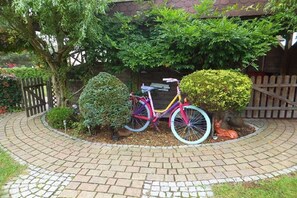 A paved circular driveway with a bicycle parked beside a neatly trimmed bush. - Holiday apartment Hehl (Born)