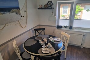 A dining area with a round table set for four, chairs, a hanging light fixture, and a window with a view of the outdoors. - Holiday home in Maasholm with swimming pool (Maasholm)