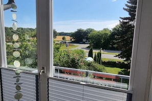 A view from a window with a balcony, overlooking a parking area and greenery. - Holiday home in Maasholm with swimming pool (Maasholm)