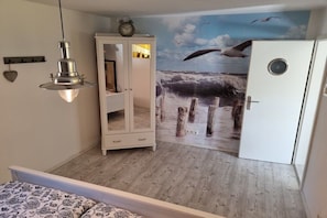 A room with a bed, a wardrobe, a wall-mounted clock, and a mural of a seascape. - Holiday home in Maasholm with swimming pool (Maasholm)