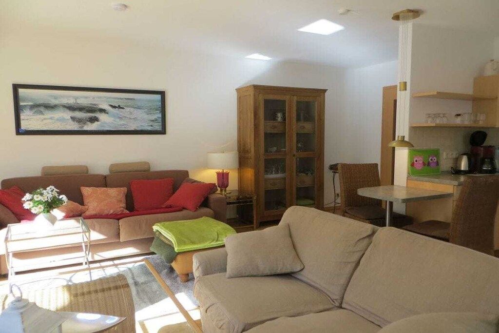 Een woonkamer met een bank, een kast, een tafel en een schilderij aan de muur.