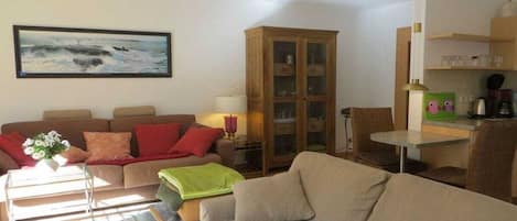Una sala de estar con sofá, aparador, mesa y un cuadro en la pared.