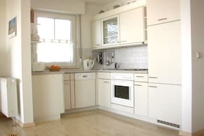 A kitchen with white cabinets, a window, and a built-in oven. - A holiday with only a sea view (Sassnitz)