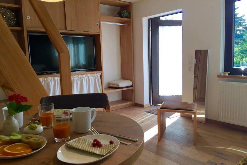 A room with a dining table set for breakfast, a television, and a window with a view.