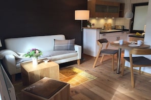 A modern living room with a sofa, coffee table, and a small dining area with chairs and a table. - Holiday home with 1 bedroom (Rechlin\/ Boek)