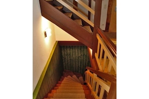 A wooden staircase with a handrail and a light fixture on the wall. - Zum Grünen Hirsch Stolln (Breitenbrunn OT Rittersgrün)