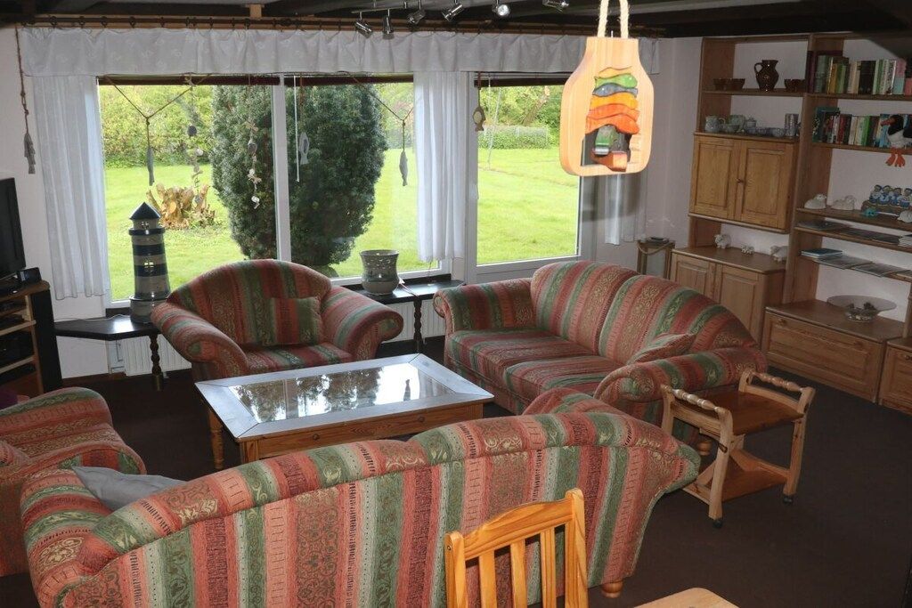 A living room with striped sofas, a glass coffee table, and a bookshelf.