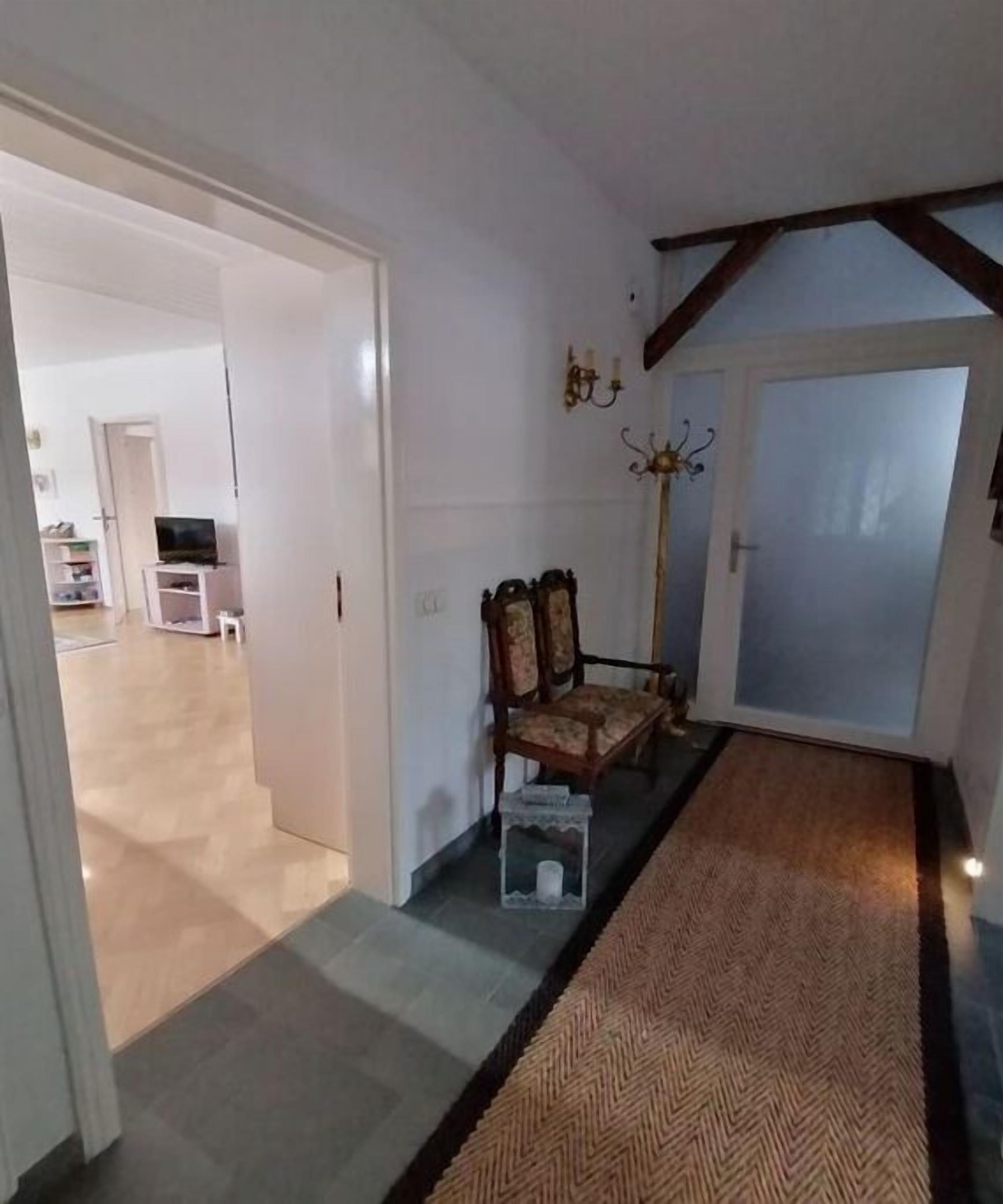 A hallway with a wooden bench, a rug, and a door leading to another room.