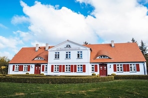 A two-story building with a symmetrical facade, red shutters, and a central entrance. - Holiday apartment in Born with sauna (Born)