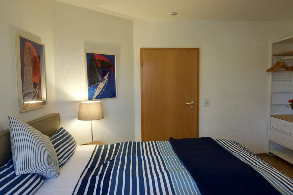 Ein Schlafzimmer mit einem Bett, einer Nachttischlampe, einer Holztür und einem Kleiderschrank.