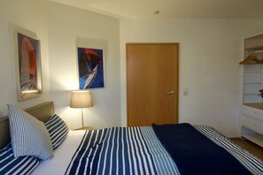A bedroom with a bed, a bedside lamp, a wooden door, and a wardrobe. - Holiday apartment with 2 bedrooms (Juliusruh)
