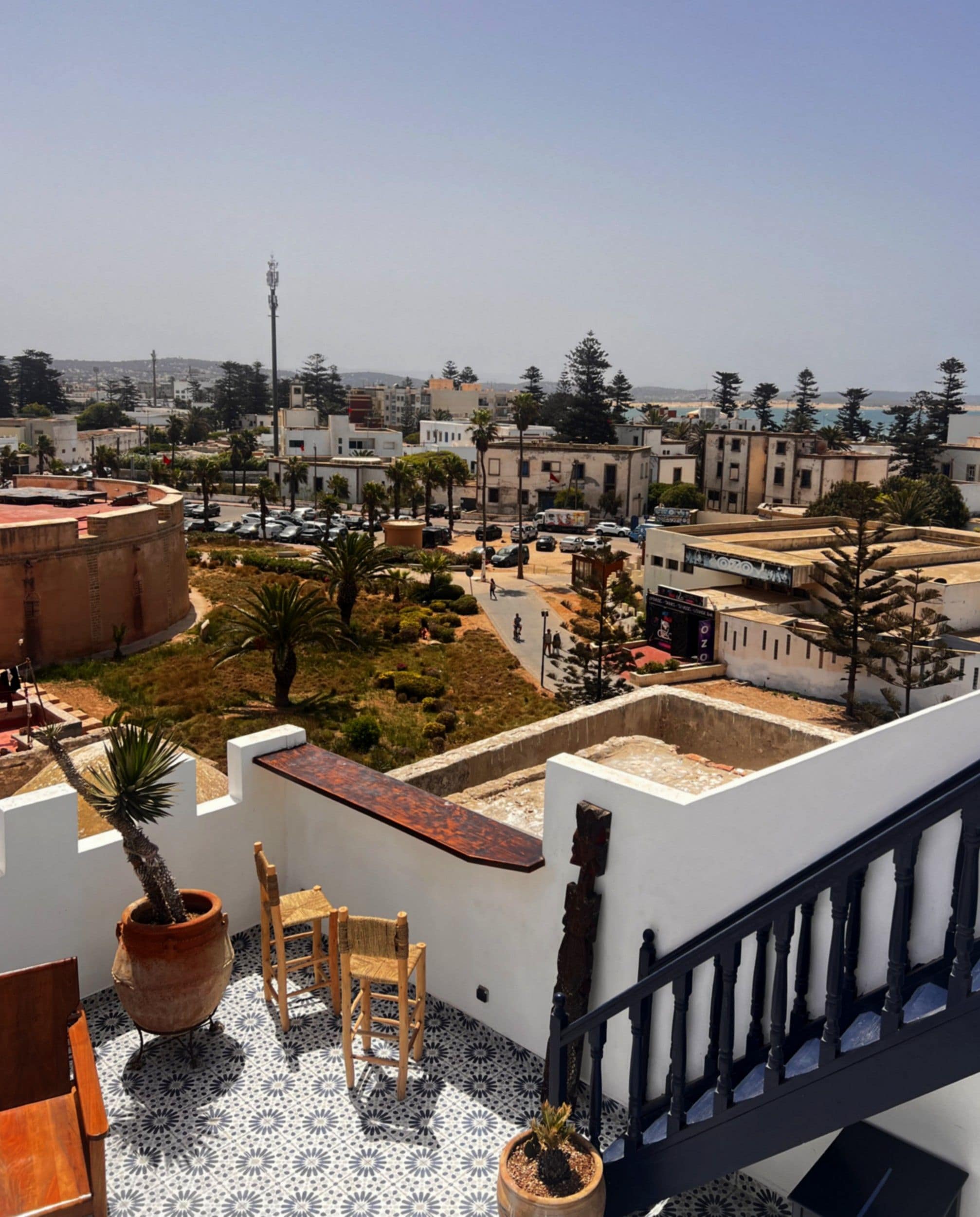 Una terraza con planta en maceta, sillas de madera y suelo de baldosas.