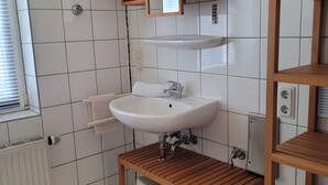 A bathroom with a white sink, a wooden vanity, and a window with blinds. - Apartment 'Zinnowitz, Dünenstraße WE 15' with Balcony and Wi-Fi (Zinnowitz)