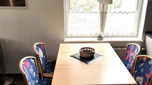 Ein Esstisch mit gewebtem Korbschmuck in der Mitte, umgeben von Stühlen mit floraler Polsterung.