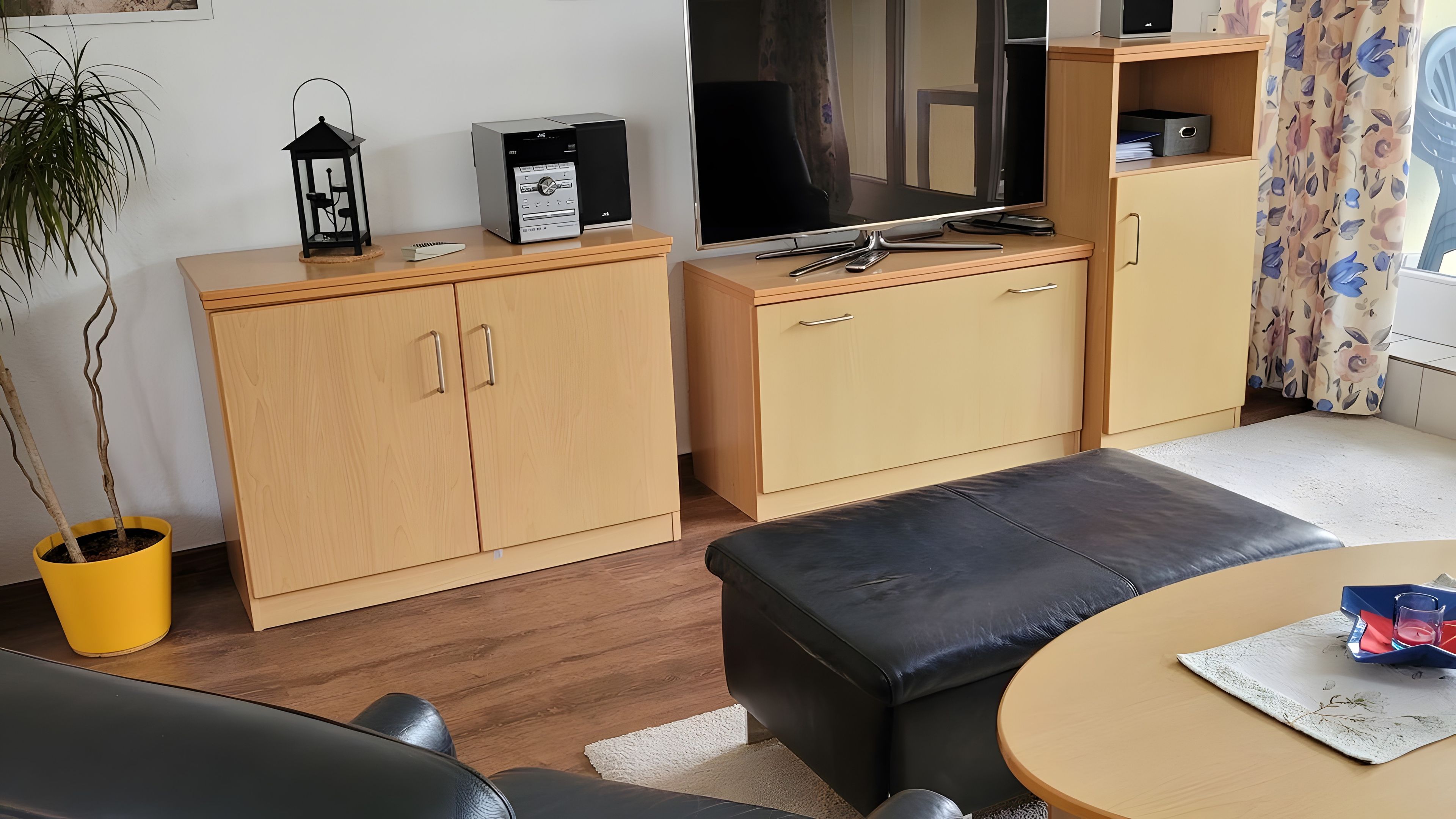 Ein gemütlicher, kompakter Wohnbereich mit einer Couch, einem kleinen runden Tisch, einem Fernseher und einem Schrank.