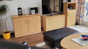 A compact living space with a sofa, a small round table, a TV, and a cabinet. - Apartment 'Zinnowitz, Dünenstraße WE 15' with Balcony and Wi-Fi (Zinnowitz)