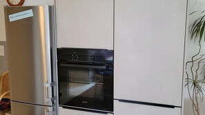 Eine Küche mit einem Edelstahl-Kühlschrank und einem schwarzen Backofen.