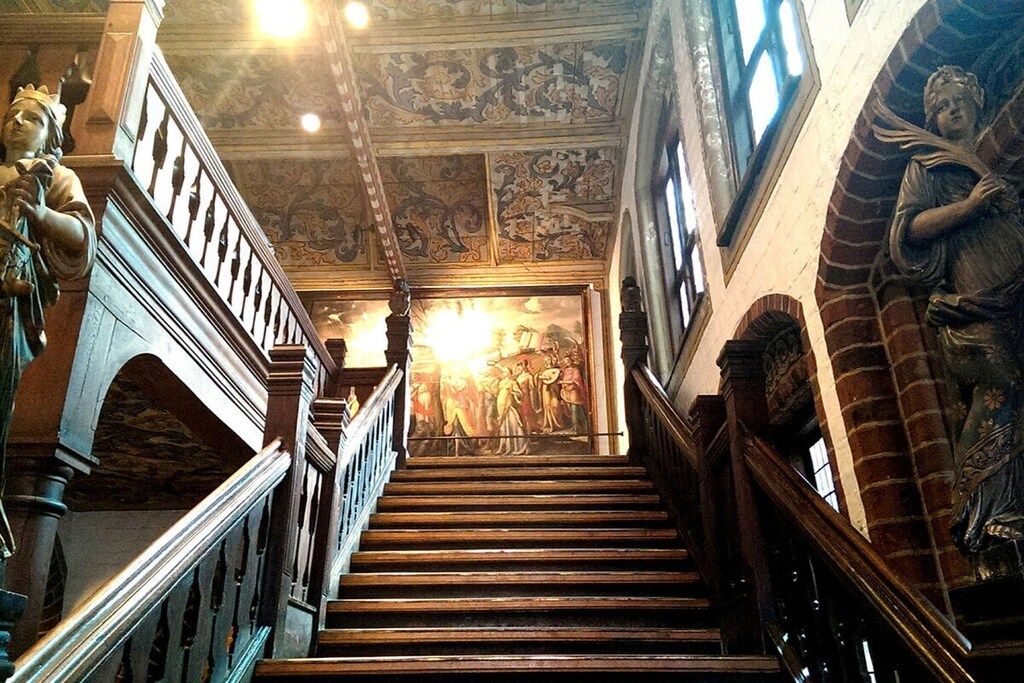 A grand staircase with ornate railings and a mural at the top.