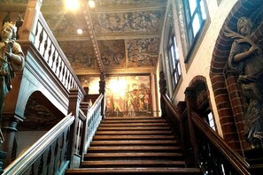 Un magnifique escalier avec des rampes richement décorées et une fresque murale au sommet.