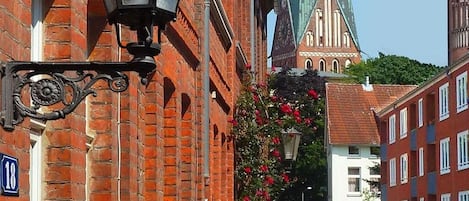 Una calle con un edificio de ladrillo rojo, una iglesia con aguja verde y un farol.