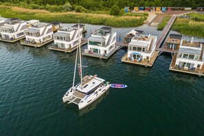 A marina with floating houses connected by walkways, a sailboat docked, and a small motorboat. - Holiday home with 2 bedrooms (Bitterfeld-Wolfen)