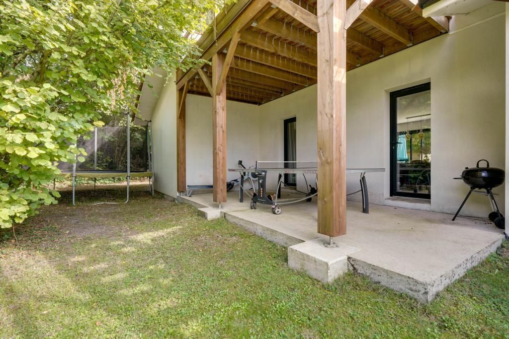 Une terrasse extérieure couverte, équipée d’un barbecue, d’une table et d’un banc.
