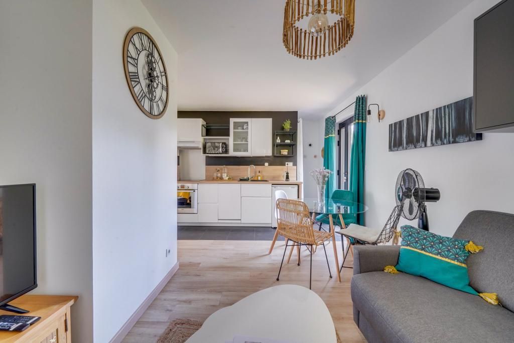 Un salon moderne comprenant un canapé, un téléviseur et un coin repas avec une chaise et une table.