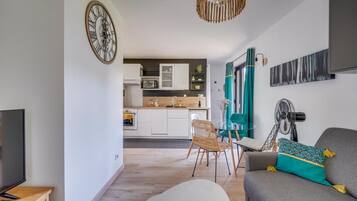 Un salon moderne comprenant un canapé, un téléviseur et un coin repas avec une chaise et une table.