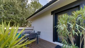 A modern outdoor deck with a dining table and chairs, surrounded by potted plants. - Le Maobi · Quiet 2-bedroom apartment with a terrace and parking, 15 minutes from Bordeaux (Tresses, 33370)