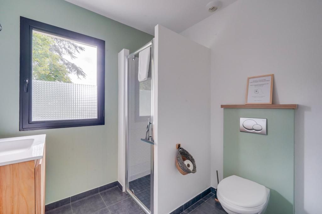 Ein Badezimmer mit Dusche, Toilette und einem Fenster.