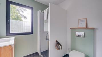 Ein Badezimmer mit Dusche, Toilette und einem Fenster.