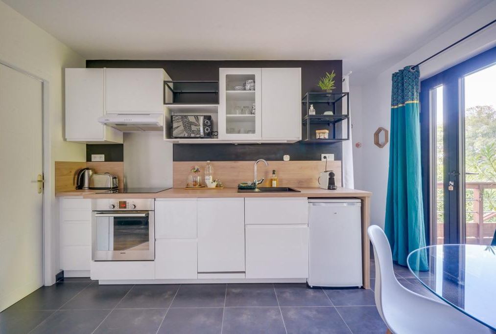 Une cuisine moderne avec des meubles blancs, un four encastré et un lave-vaisselle.