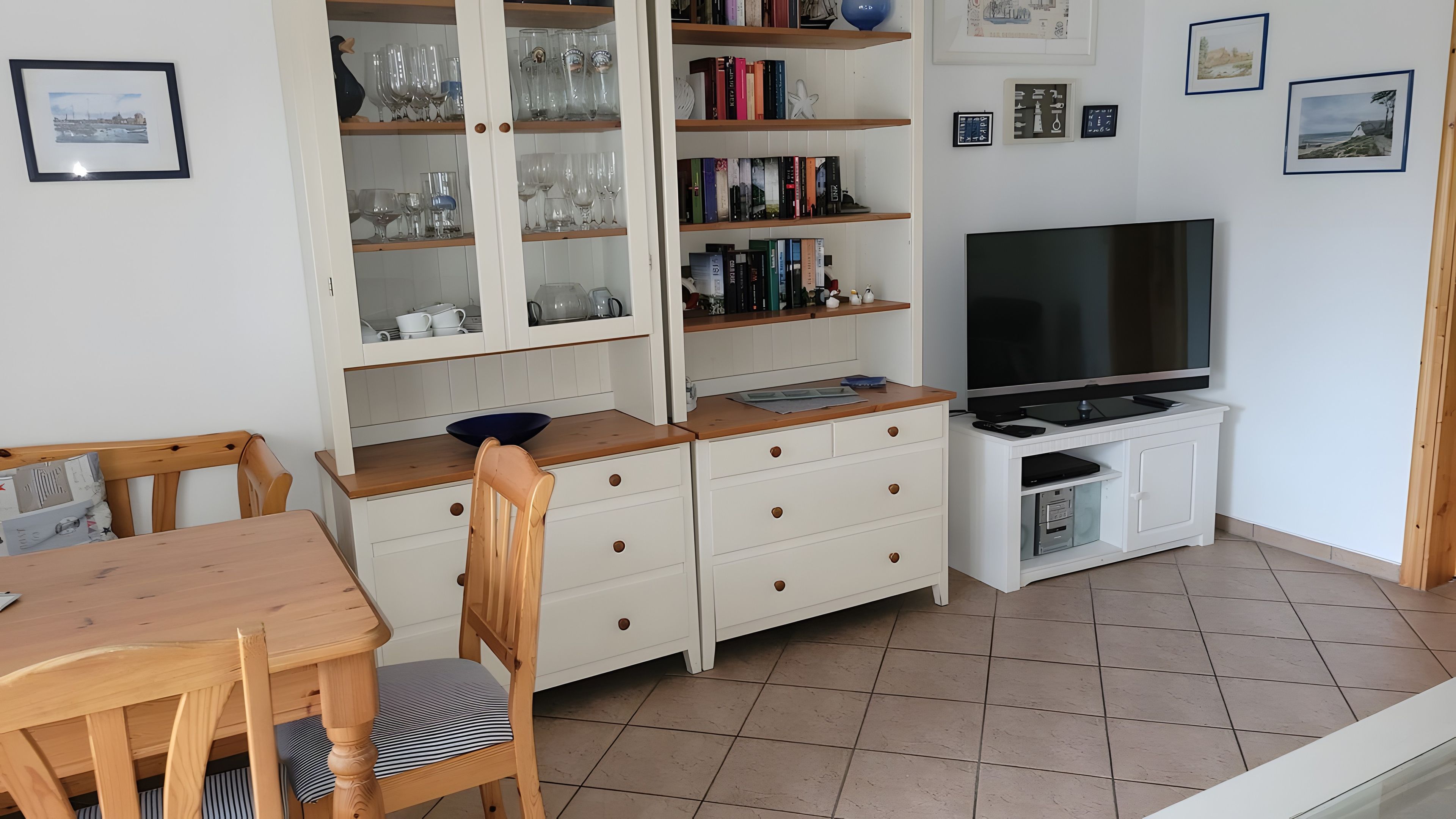 A compact living space with a dining area, a TV, and a bookshelf filled with books and decorative items.