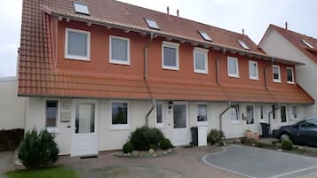 Ein zweistöckiges Gebäude mit rotem Ziegeldach, zahlreichen Fenstern und einer gepflasterten Auffahrt.