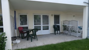 Un patio techado con mesa y sillas, un tendedero y una cerca blanca con diseño de celosía.