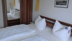 Een hotelkamer met een bed, nachtkastje, spiegel en een ingelijste foto aan de muur.