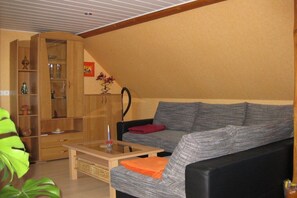 Ein Wohnzimmer mit einer Couch, einem Couchtisch und einem Holzkabinett mit Regalen.