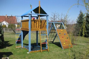 Eine hölzerne Spielanlage mit Kletterwand und Rutsche.